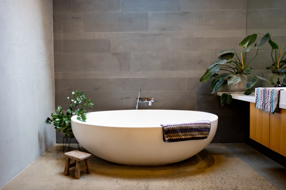 a bathtub in a bathroom with a plant in the corner