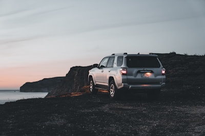 A sleek luxury SUV parked on a scenic coastal road at sunset in Latin America.