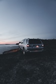 An elegant SUV parked near a beautiful lake at sunset.