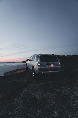 An elegant SUV parked near a beautiful lake at sunset.