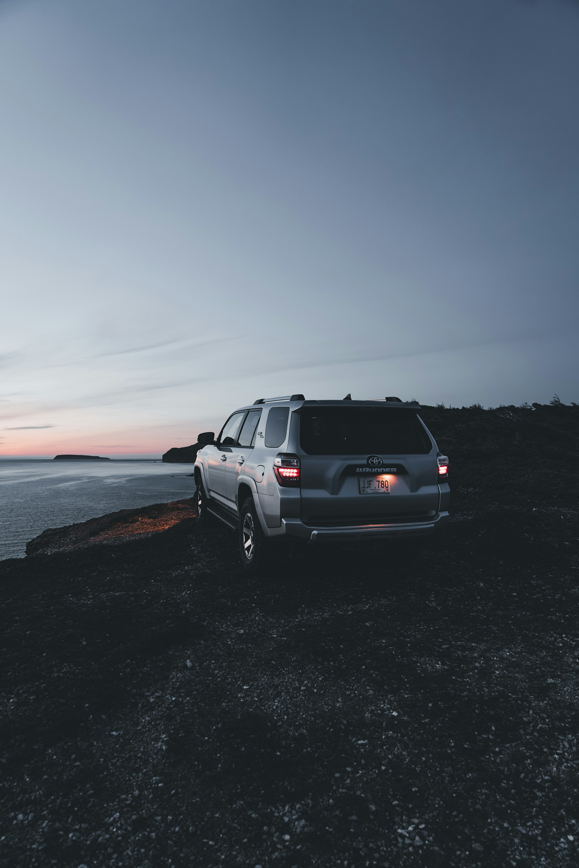 A sleek silver SUV parked by a scenic coastal road at sunset, highlighting adventure and comfort.