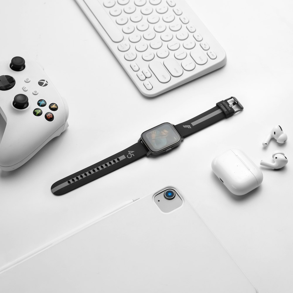 a white table with a keyboard, mouse, headphones, and a cell phone