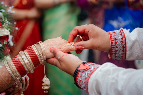 Close-up of hands adorned with henna and bangles during a wedding ritual.