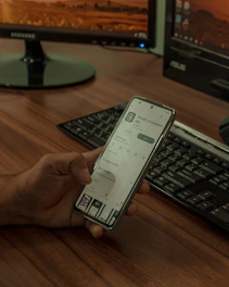 a person holding a cell phone in front of a computer
