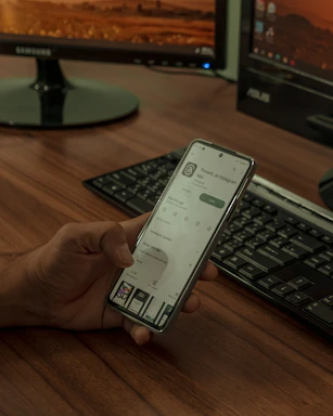 a person holding a cell phone in front of a computer