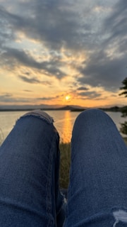 A serene scene of a person listening to music while watching a sunset by the lake.