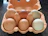 Colorful egg cartons stacked neatly with a cheerful delivery box in a cozy home setting.