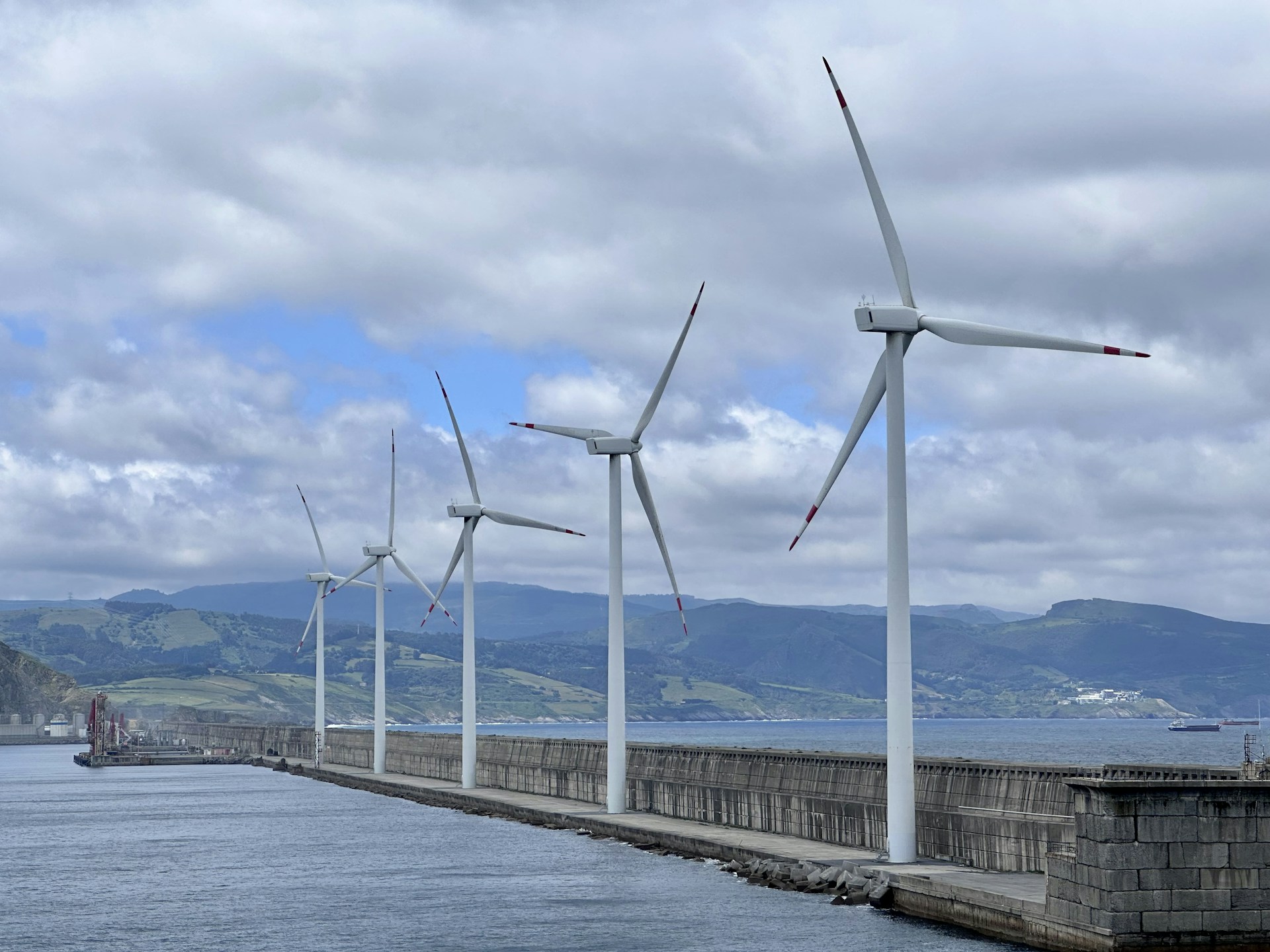 a row of wind turbines next to a body of water