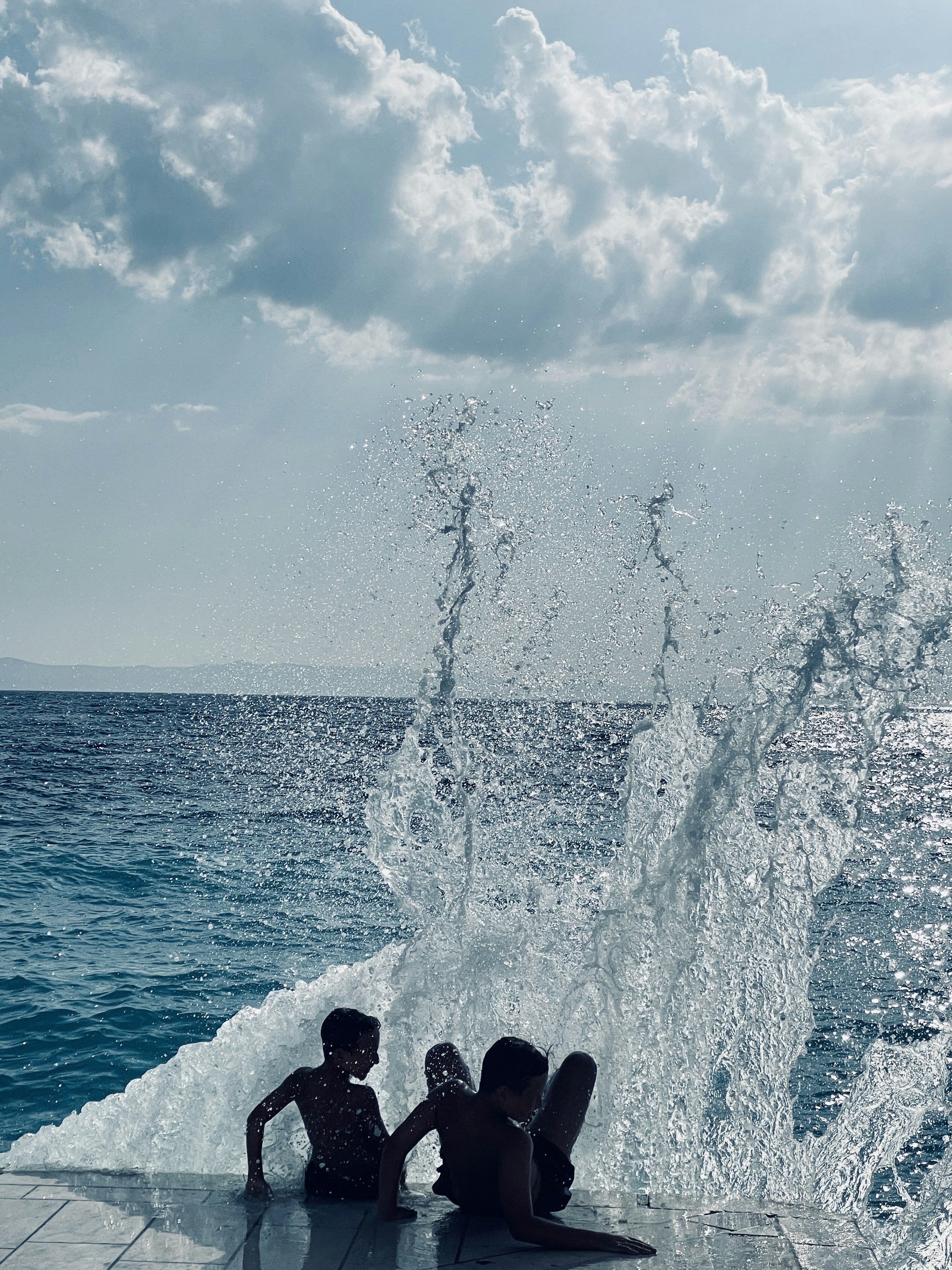 Due persone sedute sul bordo di uno specchio d'acqua