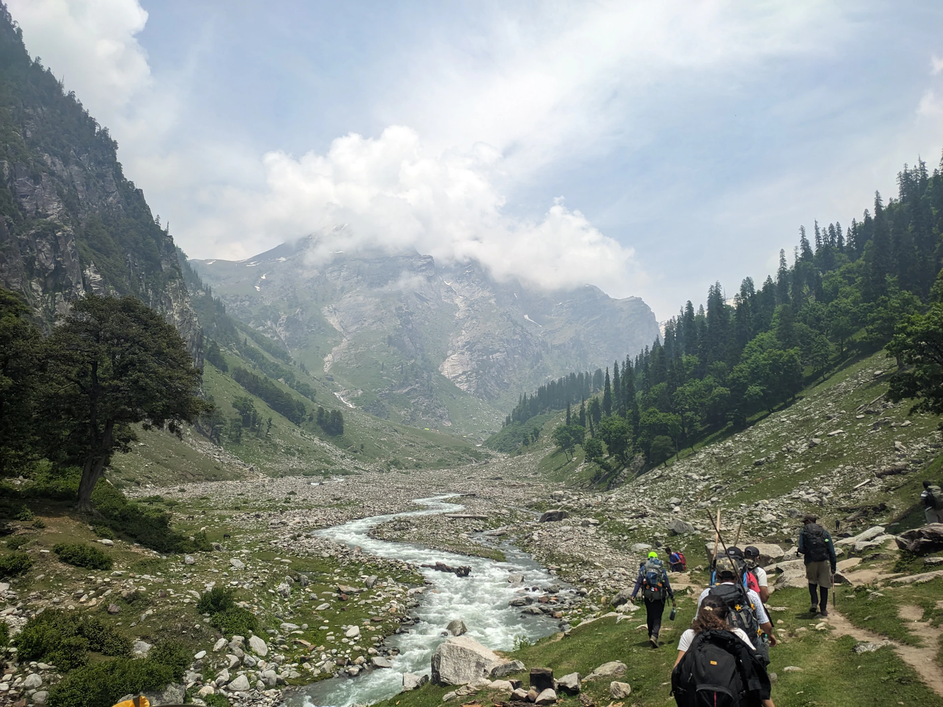 a group of people walking up a hill next to a river
