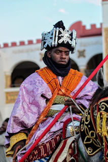 The groom arriving on a decorated horse beneath ornate palace arches during a vibrant wedding procession