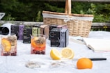 A stylish aqua flask next to fresh fruits on a picnic blanket.