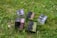 Several product boxes are placed on a grassy field. The boxes are designed with different color schemes and feature bold typography. They appear to contain cosmetics or personal care items.