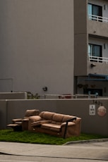 a couch sitting in the grass in front of a building