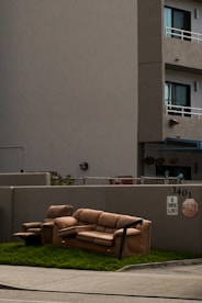 a couch sitting in the grass in front of a building