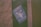 A blue sticker featuring a symbol of gender equality encircling a fist, accompanied by the text 'Destroy Patriarchy, Not the Planet' is adhered to a green surface.