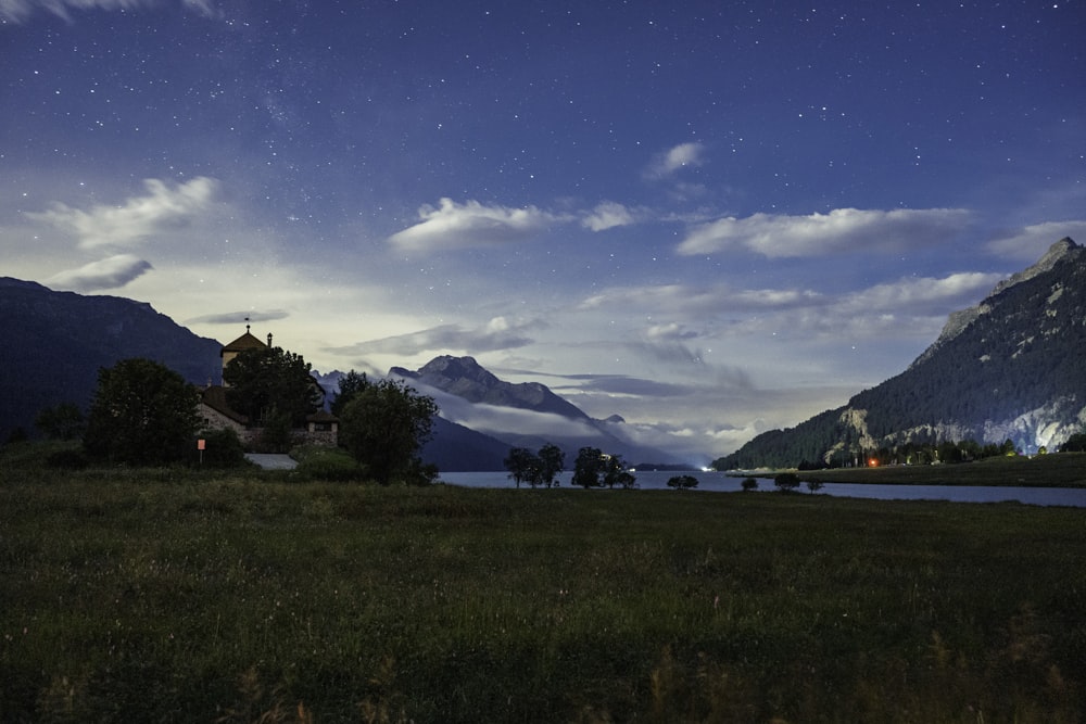 a grassy field with a lake and mountains in the background