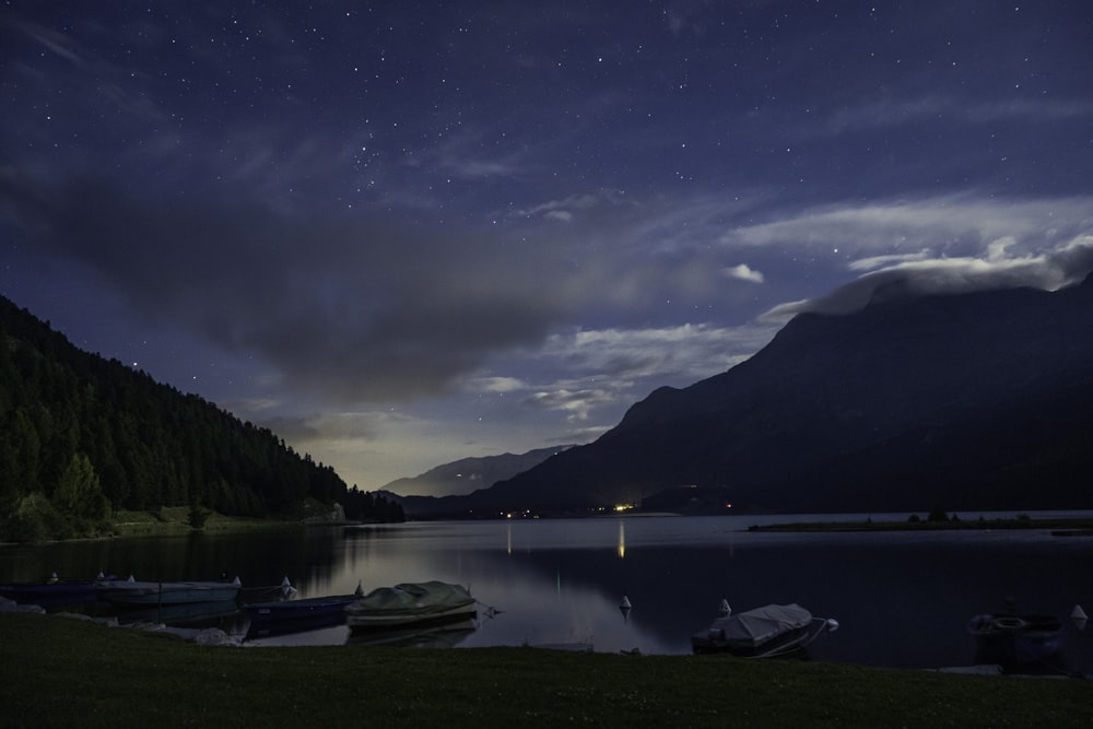 a group of boats sitting on top of a lake under a night sky