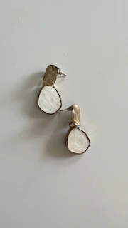 Pair of gold earrings with a modern design showcased against a subtle gold-toned backdrop