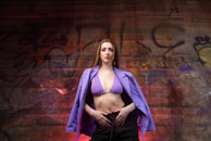 A plus size woman confidently posing in front of a vibrant urban mural.