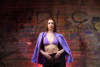 A plus size woman confidently posing in front of a vibrant urban mural.