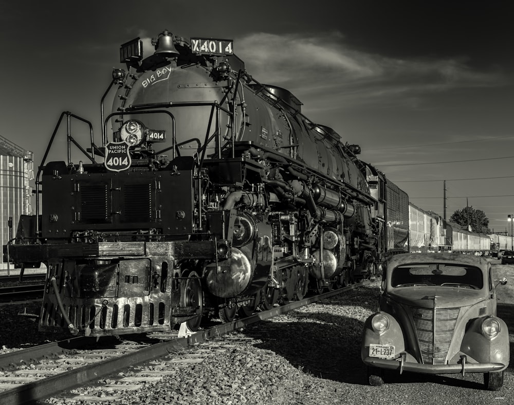 a black and white photo of a train and a car