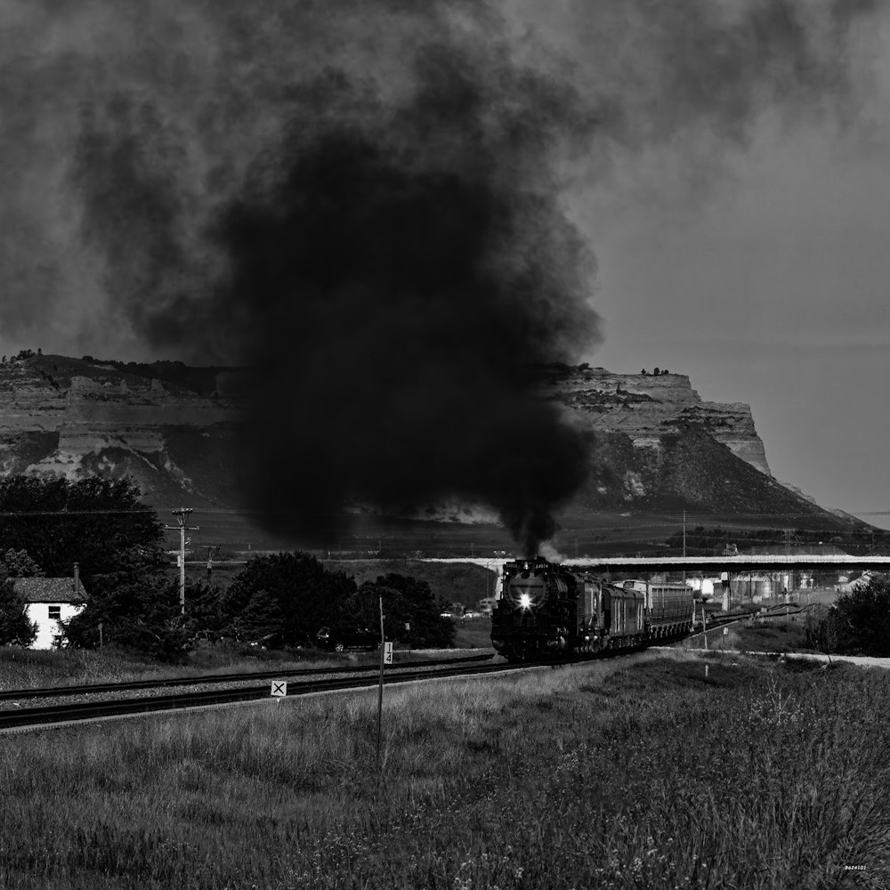 a train traveling down train tracks next to a mountain