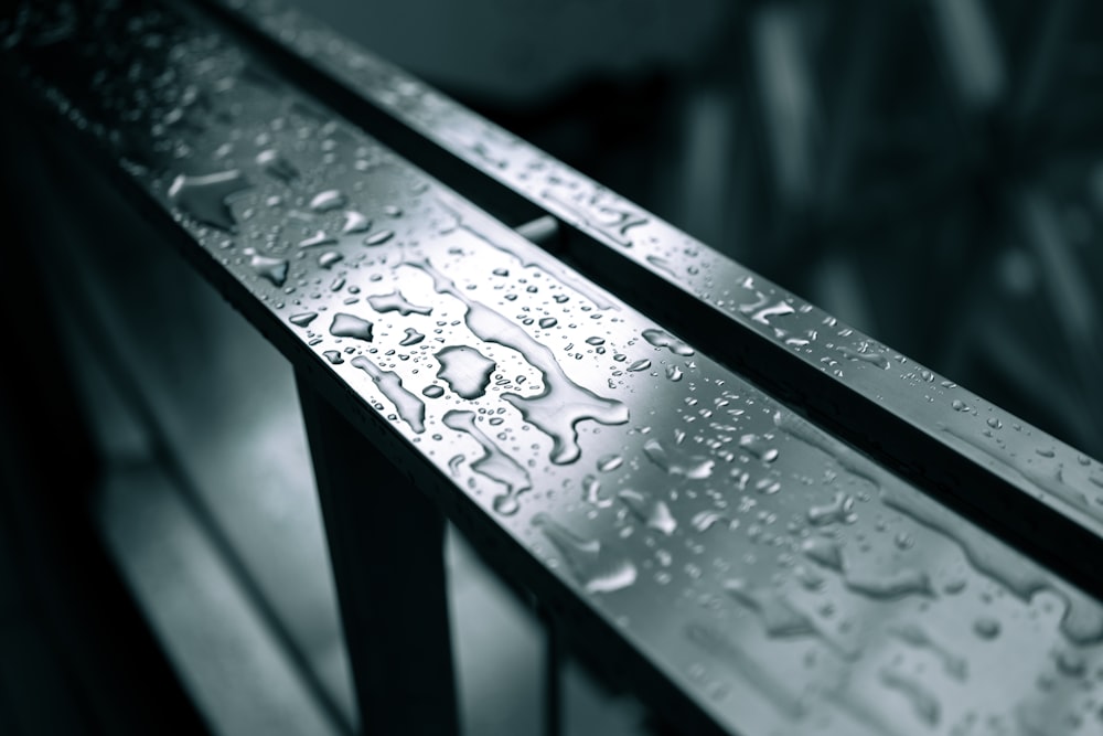 a close up of water droplets on a metal railing