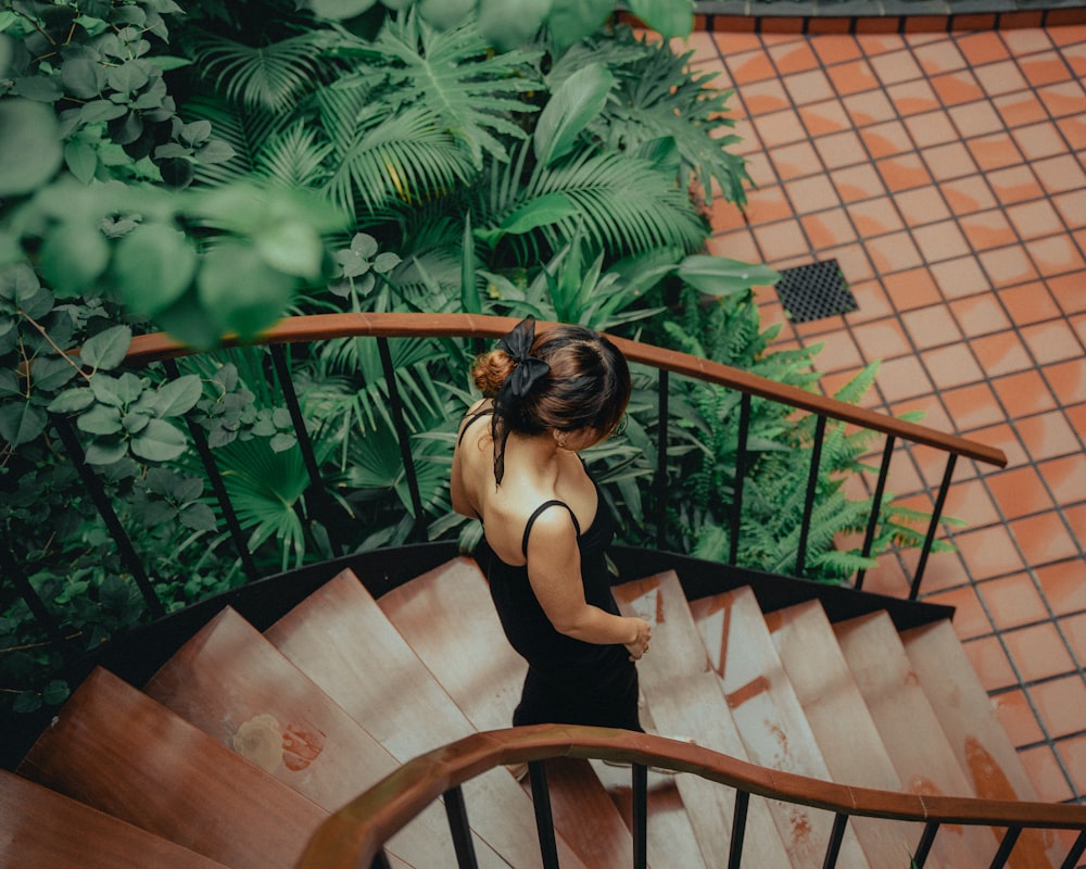 a woman in a black dress walking down a set of stairs