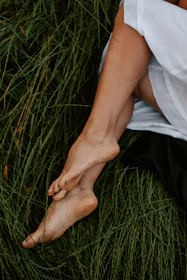 A warm sunlit scene with a person barefoot on grass, embodying natural living.