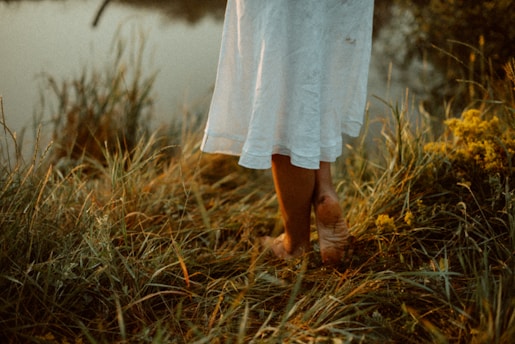a woman in a white dress is standing by the water