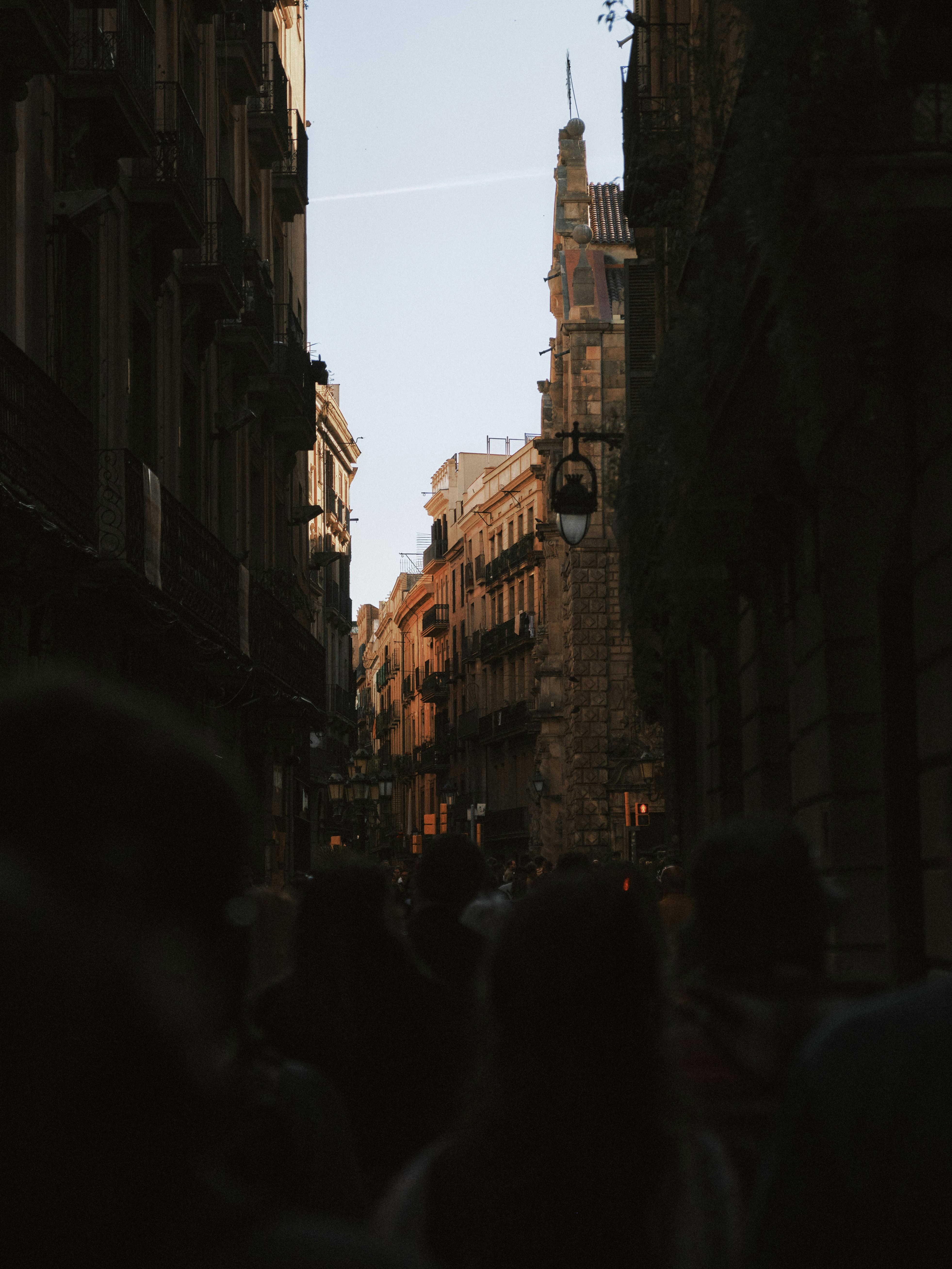 A group of people walking down a street next to tall buildings photo ...