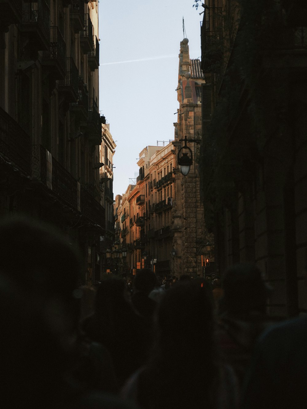 a group of people walking down a street next to tall buildings