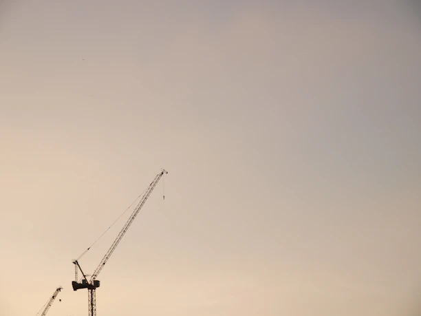 Modern construction cranes working against a clear blue sky during a bright day.