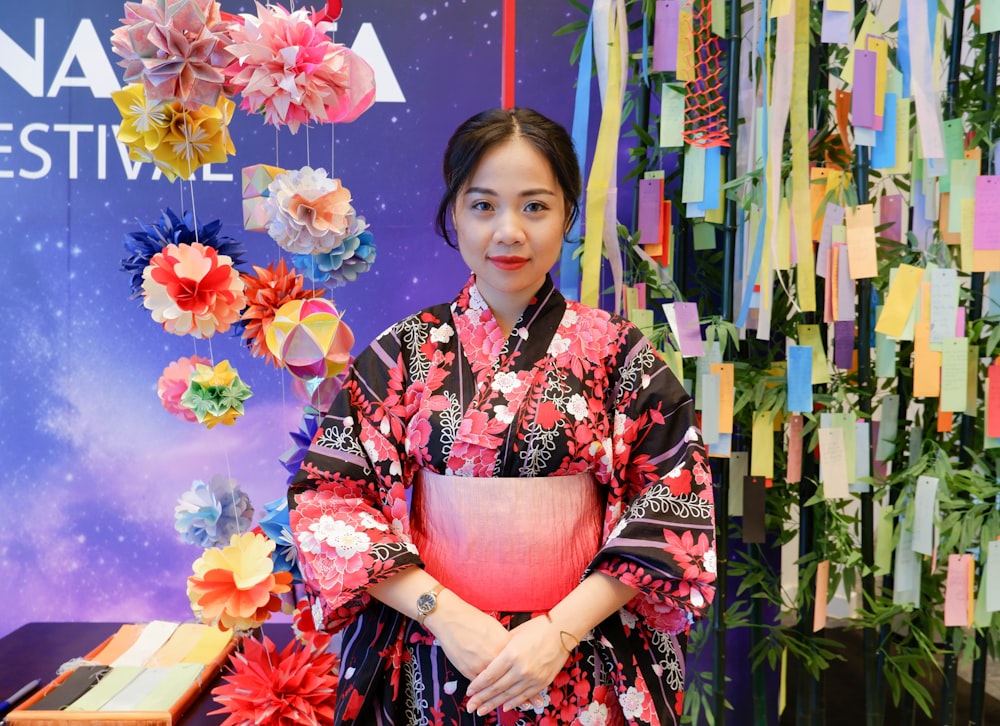 a woman standing in front of a display of paper flowers