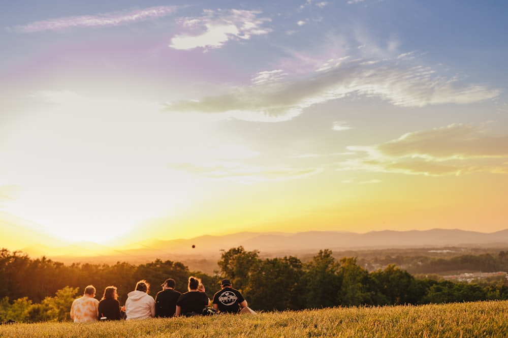 a group of people sitting on top of a lush green field