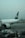 A large passenger airplane is parked at an airport terminal. The plane has the marking 'PIA' on its tail and 'INTERNATIONAL' along its fuselage. Ground support equipment, such as a mobile stairway and service vehicles, are positioned near the aircraft. The sky is overcast, giving a muted and calm atmosphere to the scene.