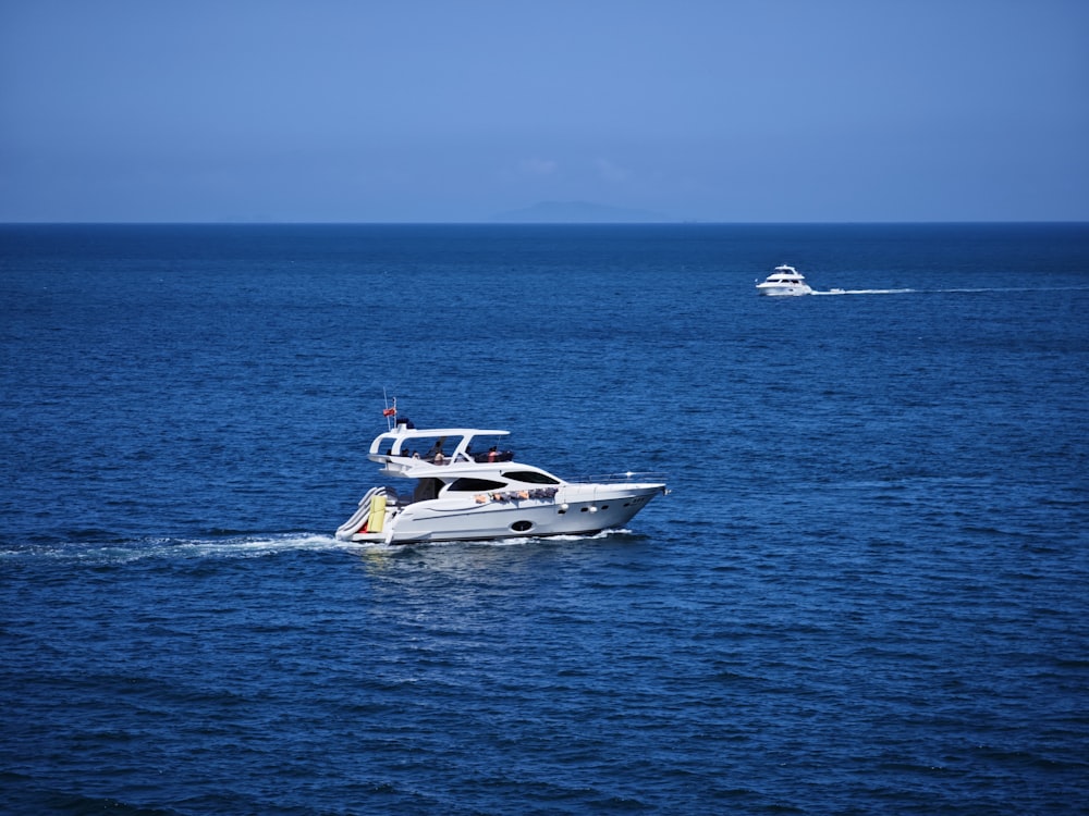 a boat in the middle of the ocean with a speedboat in the background