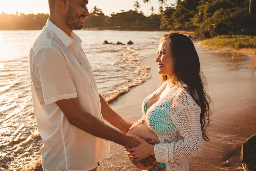 a man and a woman holding hands on the beach