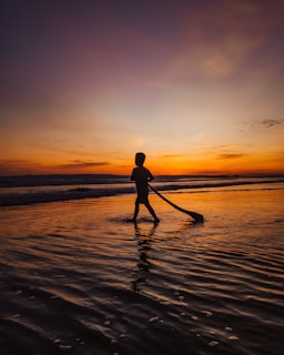 Sunset shot of a woman in a stylish beach cover-up walking along the shoreline