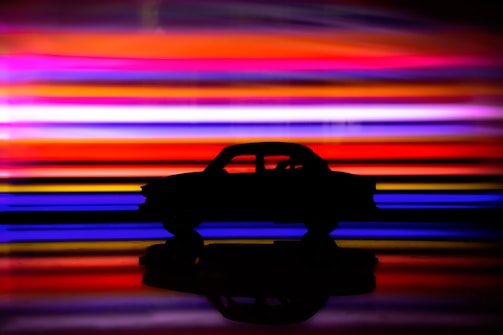 Artistic silhouette of a vintage car against a simple, muted background.