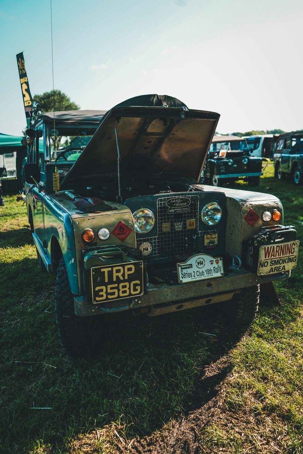 Un jeep con capó abierto sentado en la hierba