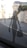 A perforated silhouette of a stylish woman carrying shopping bags is adhered to a glass window. Beyond the glass, a blurred urban street view with historic architecture is visible.