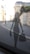 A perforated silhouette of a stylish woman carrying shopping bags is adhered to a glass window. Beyond the glass, a blurred urban street view with historic architecture is visible.