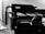A monochrome image of a black multifunction printer with the brand name visible on the top. The printer displays a control panel and an open paper tray. It is positioned against a plain wall with a small portion of a person or object partially visible in the foreground.