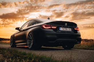 A powerful gold-accented sports car parked on a desert road at sunset.