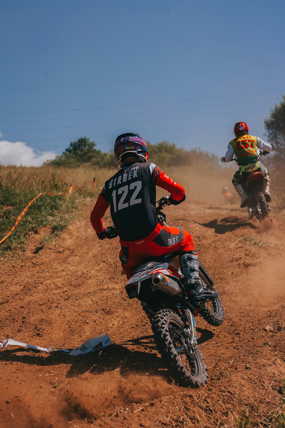 two people riding dirt bikes on a dirt track