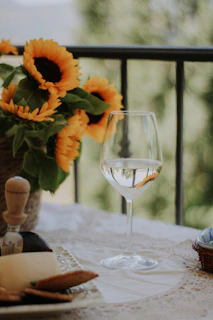 White wine bottle with honey drizzles and fresh flowers on a light wooden table.