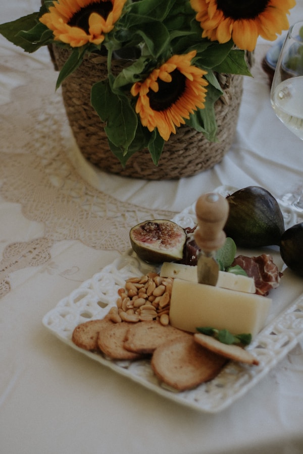 A plate of cheese, crackers and sunflowers on a table