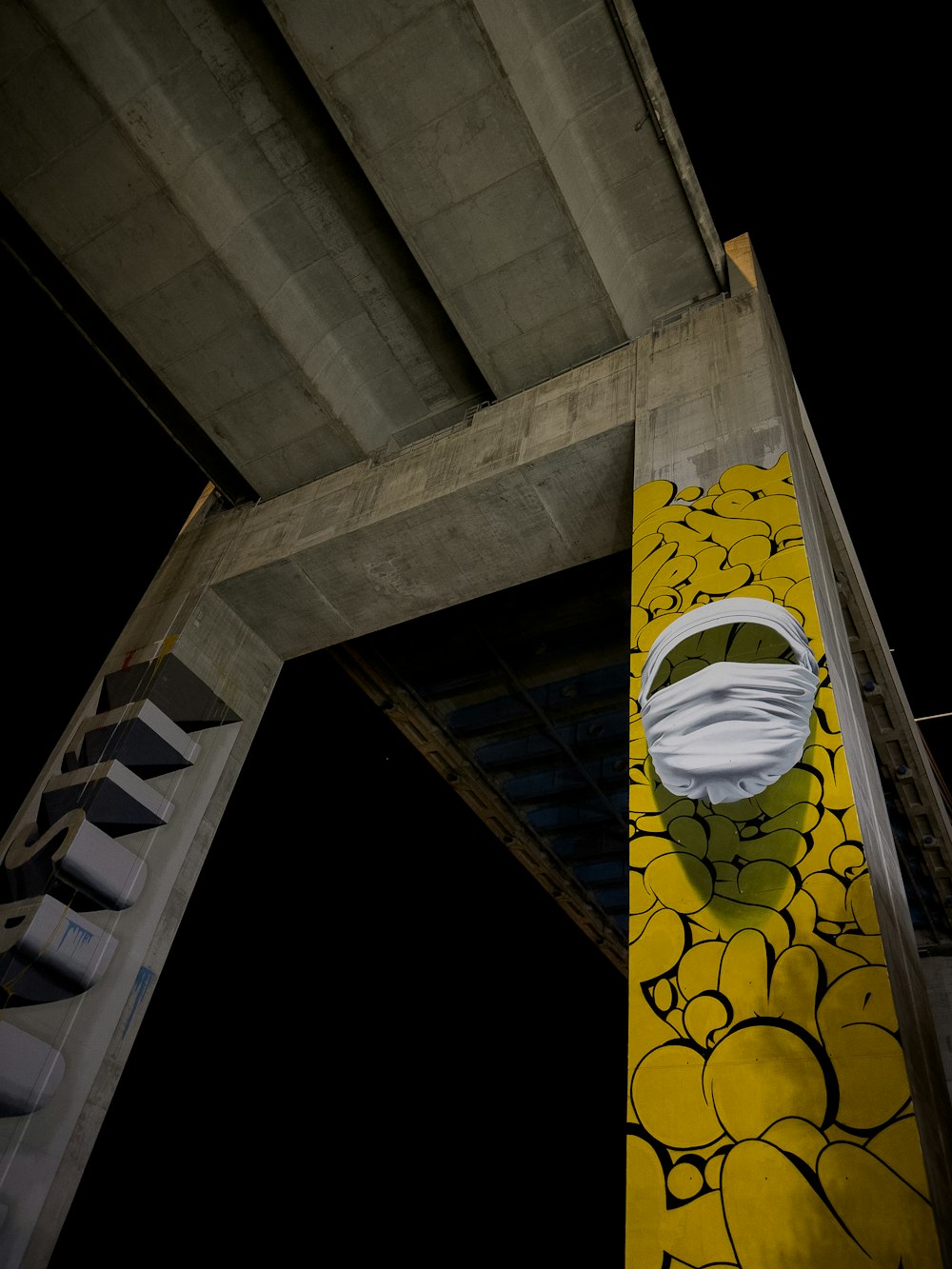 a yellow and white mural on the side of a bridge